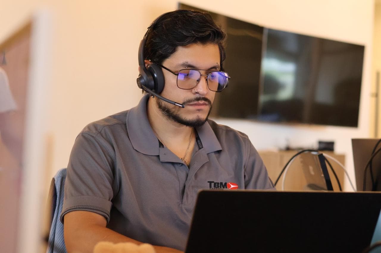 Un despachador de TBM Carriers con polo de la marca y diadema coordinando un envío transfronterizo